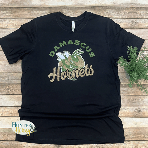 A black short sleeve 100% ringspun cotton t-shirt featuring a 3-color glitter design across the front that reads Damascus Hornets and features the hornet in the center.