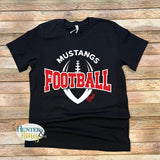 A black short-sleeve t-shirt with a 'Mustangs Football Dad' graphic, laid flat on a rustic wooden plank background. The graphic features a white football silhouette and the words 'MUSTANGS FOOTBALL' in white and red, with 'Dad' written in red script.